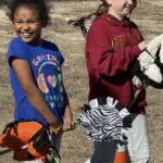 Smiling children with zebra and pumpkin hobby horses